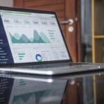 Alt-Text: Geöffneter Laptop auf einem Glastisch, der ein Dashboard mit Geschäftsanalysen und Statistiken anzeigt. - Seeberger Marketing